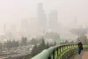 A woman walks across the Jose Rizal Bridge as a blanket of wildfire smoke obscures the view of the Seattle skyline, Friday,