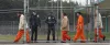Inmates walk past correctional officers at the Washington Corrections Center in Shelton, Wash., in this photo from February