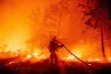 A firefighter douses flames as they push towards homes during the Creek fire in the Cascadel Woods area of unincorporated