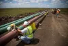Construction workers specializing in pipe-laying work on a section of pipeline on July 25, 2013 outside Watford City, North